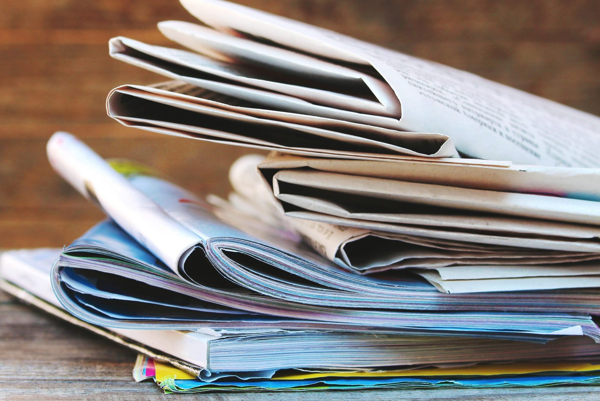  Newspapers and magazines on old wood background. Toned image. 