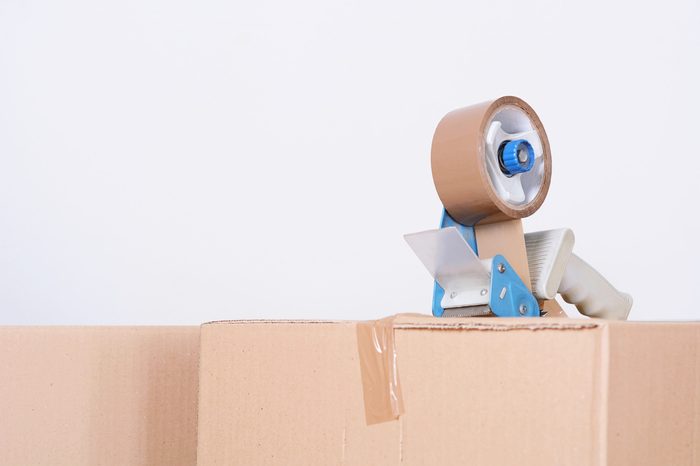 Tape dispenser sealing a shipping cardboard box. Indoors