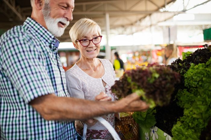 Smiling senior couple buying vegetables and at the merket