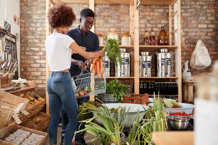 Couple Buying Fresh Fruit And Vegetables In Sustainable Plastic Free Grocery Store