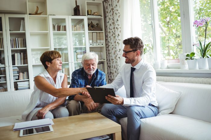 Financial advisor shaking hands with senior woman in living room