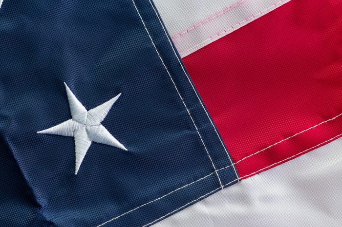 American national flag folded to show a single star representing one of the original 13 colonies and red, blue and white stripes in a full frame background view