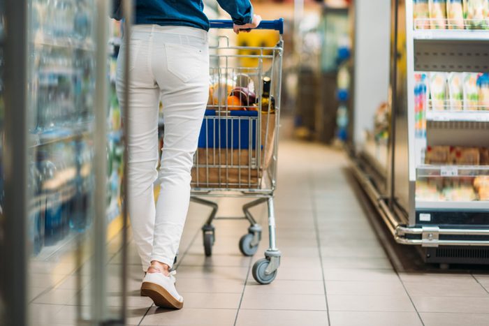 cropped shot of woman with shopping cart walking in supermarket