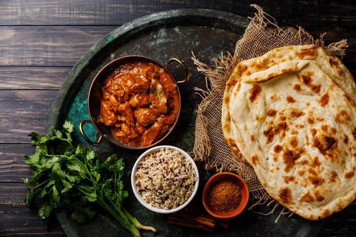 Chicken tikka masala spicy curry meat food with rice and naan bread on dark background