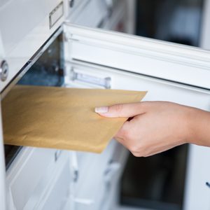 Close-up of woman's hand pulling envelop from mailbox