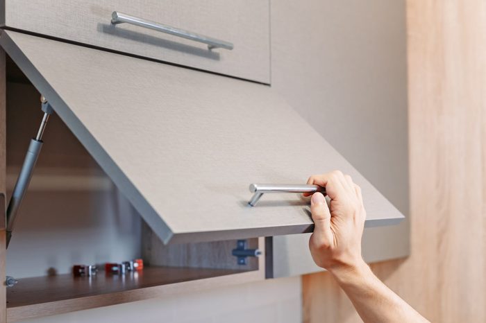 man hand open kitchen cupboard with handle, close up