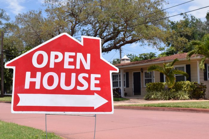 Bright red open house real estate sign in nice suburban neighborhood, sunny day.