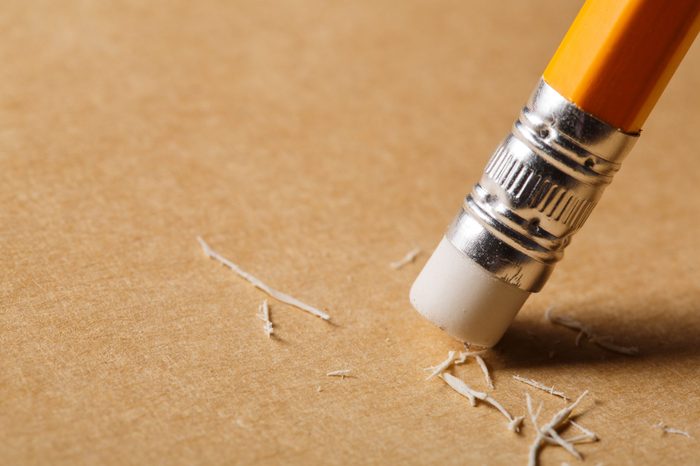 A pencil eraser removing a written mistake on a piece of paper.