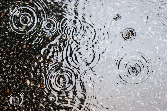 Rain on asphalt or tarmac road creating ripples, high contrast during autumn.