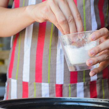 Cook takes cup of salt to water in bowl