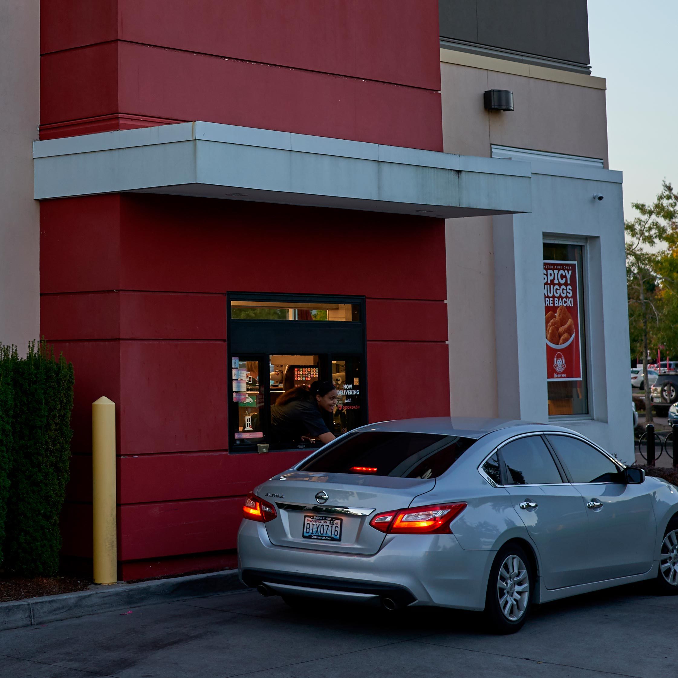 car at a wendy's drive thru window at twilight