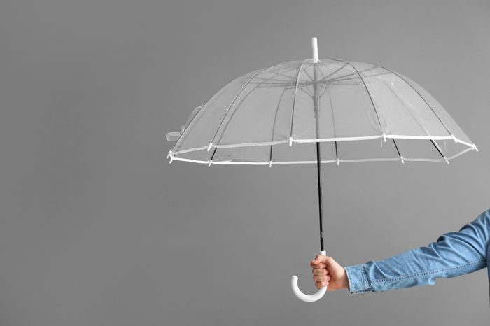 Female hand with stylish umbrella on grey background