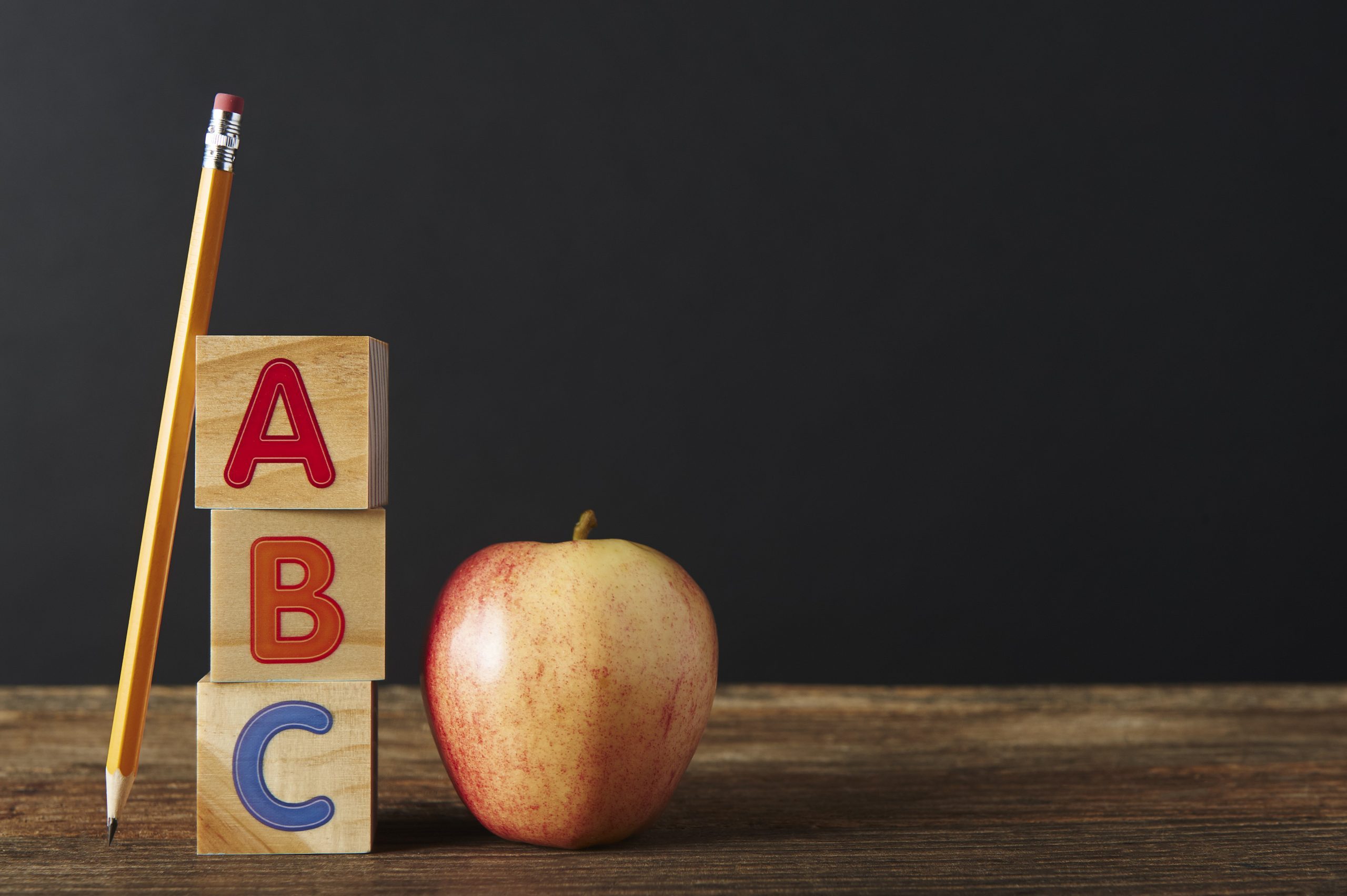 Pencil, Spelling blocks and apple on a wooden table with copy space.