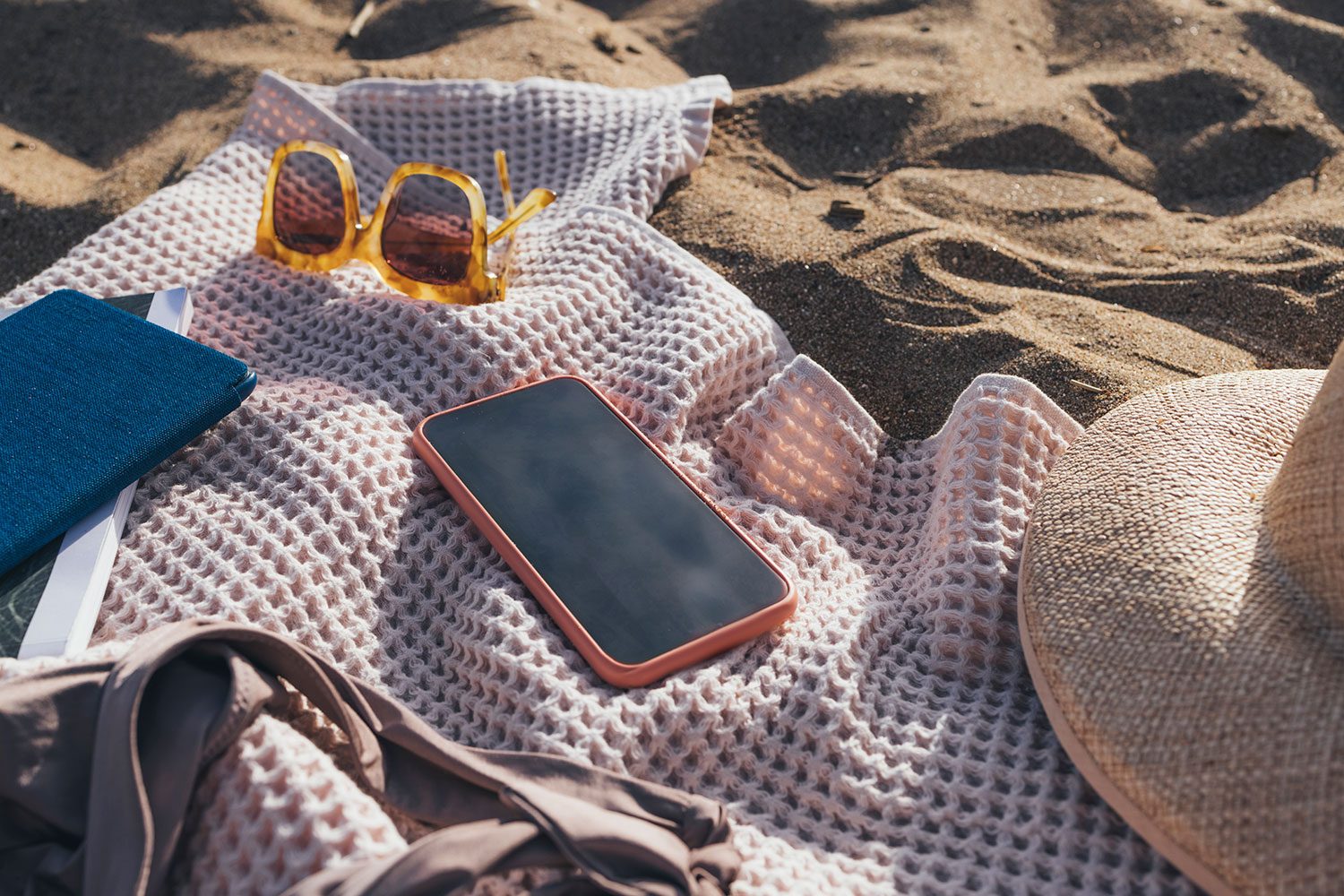 Ready For The Seaside: Beach Essentials Still Life On Sand Including hat, sandals, swimsuit, beach bag, towel and a mobile phone to stay connected