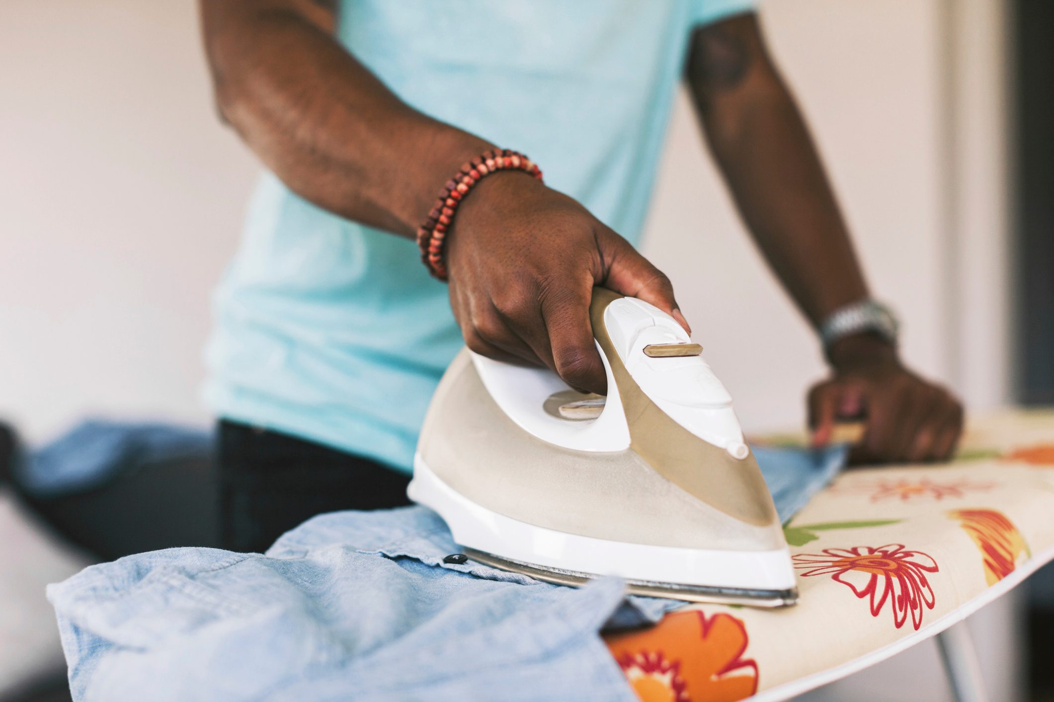 close up of man ironing clothing on ironing board at home