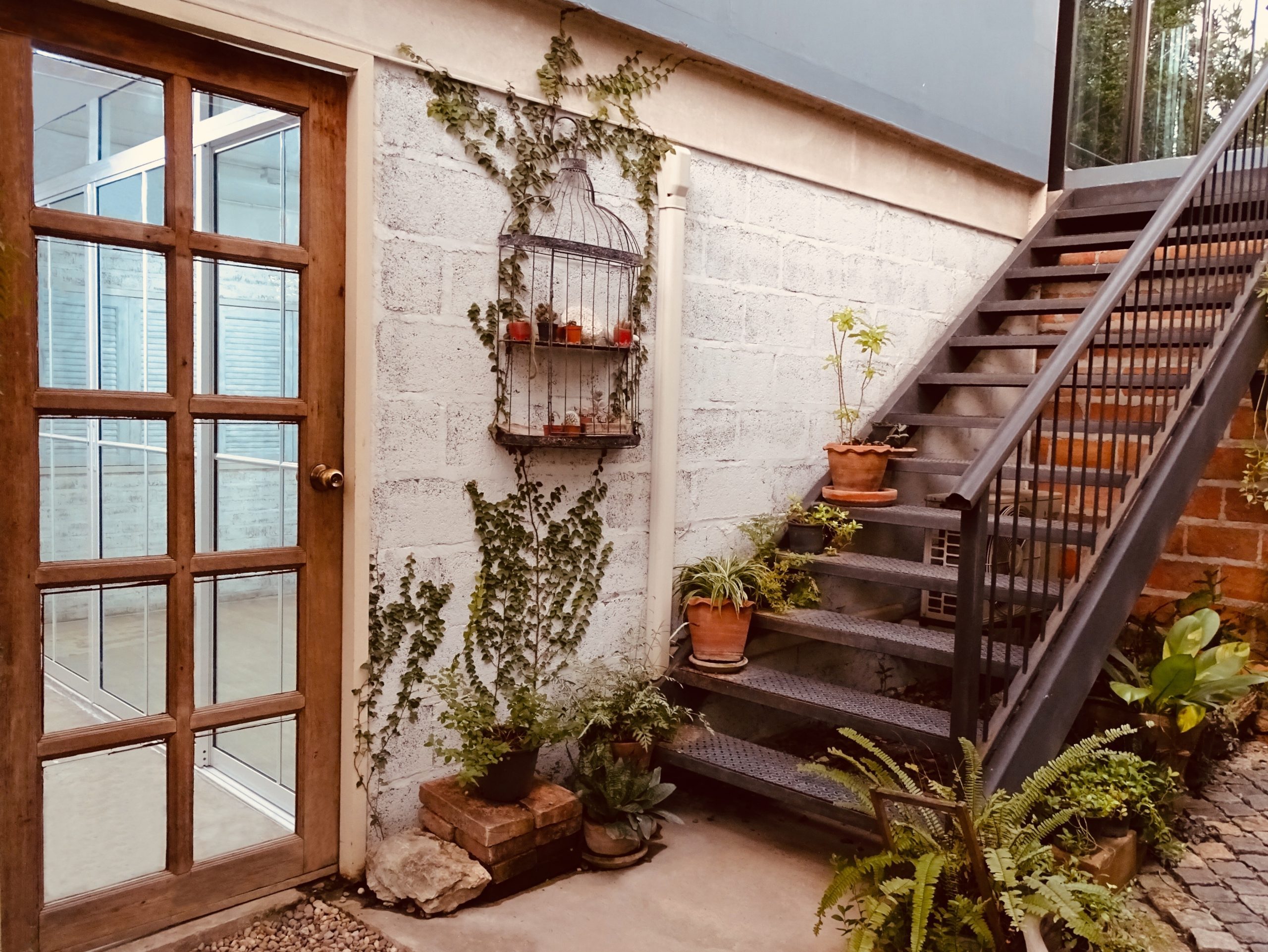 The door house and the stairs on the side. A small garden in front of the house. The beautiful exterior of a building.