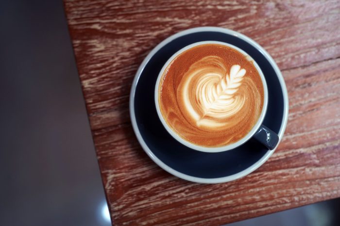 Top view of cafe latte with "Tulip" latte art in the blue ceramic cup on the wooden table.