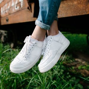 Female sneakers. White female shoes on feet. Sneakers closeup. 