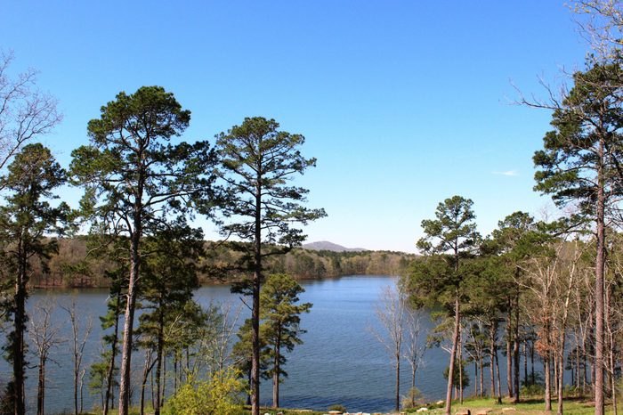 Breathtaking spring view of Lake Ouachita in Hot Springs Arkansas in foreground against blue sky. Tallest mountain in Hot Springs visible in background. 