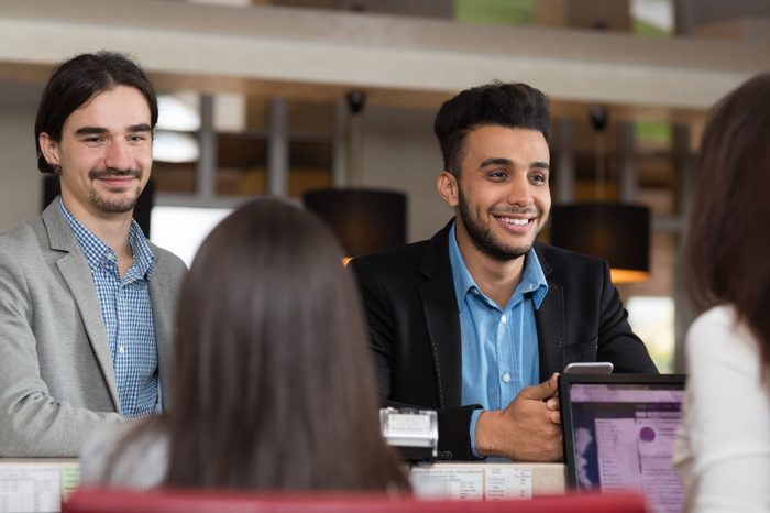 Two Business Man Arrive To Hotel Check In Woman Receptionist Registration At Reception Counter