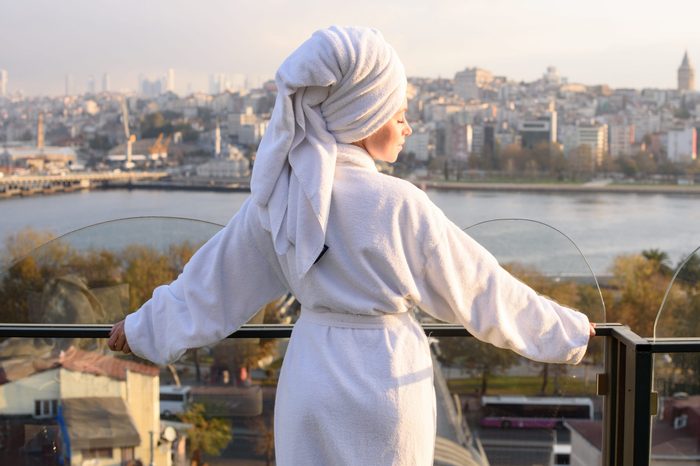 Woman in bathrobe on the terrace of a house at sunrise