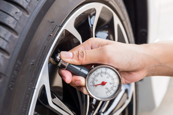 Close-Up Of Hand holding pressure gauge for car tyre pressure measurement