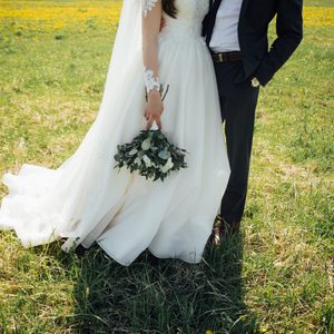 portrait of beautiful bride with wedding bouquet isolated at green natural summer field background.