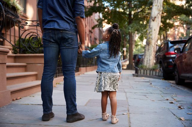 Father and daughter taking a walk down the street, back view