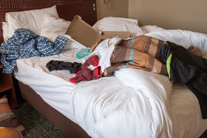 messy hotel room bed after a night of partying