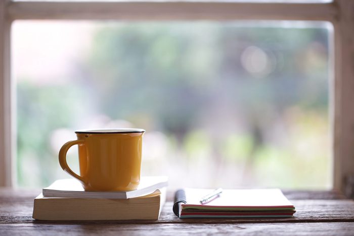 Notebook and yellow cup on wooden table