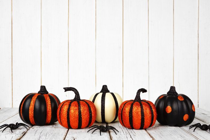 Black and orange glittery Halloween pumpkins against a white wood background