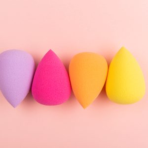 Colorful beauty sponges on pink background. Makeup tool for applying and blending products such as foundation, concealer. Horizontal shot. Copy space for text.