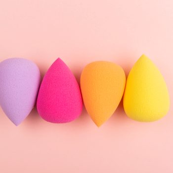 Colorful beauty sponges on pink background. Makeup tool for applying and blending products such as foundation, concealer. Horizontal shot. Copy space for text.