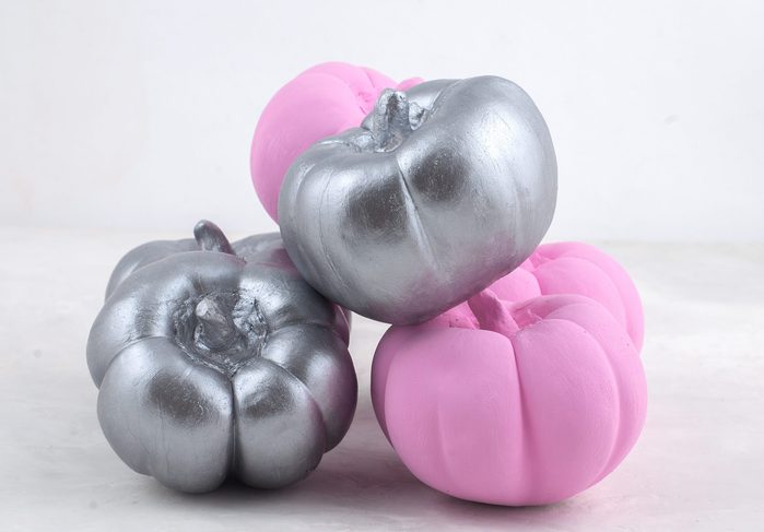 Decorative Halloween pumpkins. Painted pumpkin. Small decorative pumpkin on a marble background on the table. Composition on Halloween. Pumpkin decor. Pink and silver pumpkin.