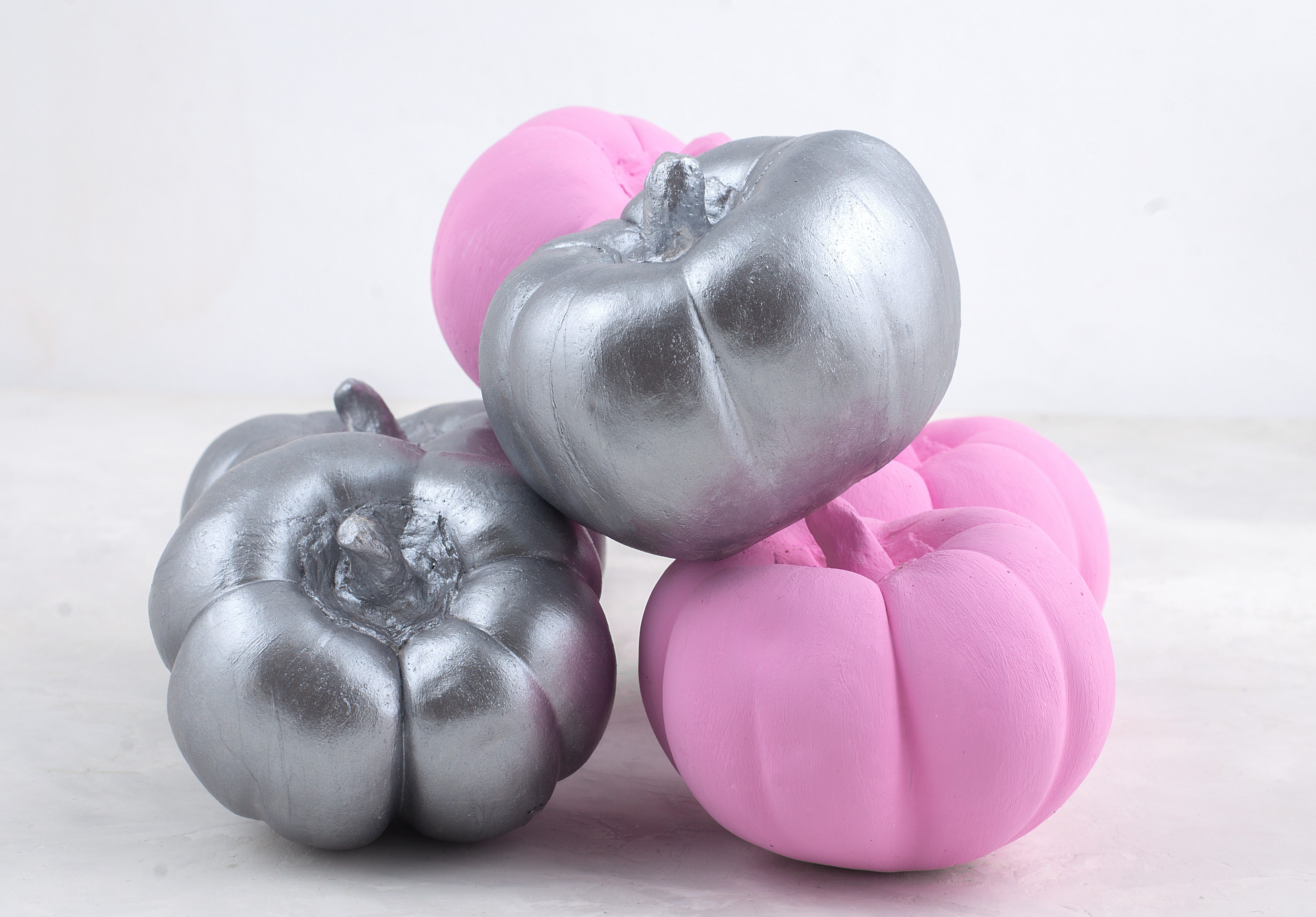 Decorative Halloween pumpkins. Painted pumpkin. Small decorative pumpkin on a marble background on the table. Composition on Halloween. Pumpkin decor. Pink and silver pumpkin.