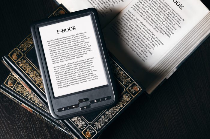 E-book reader device on desk in library. Alternative for traditional books