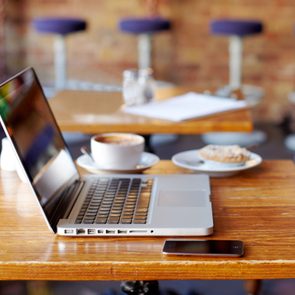 a laptop, a smartphone, a coffee, and a pastry sit on a table at a cafe with free open wifi