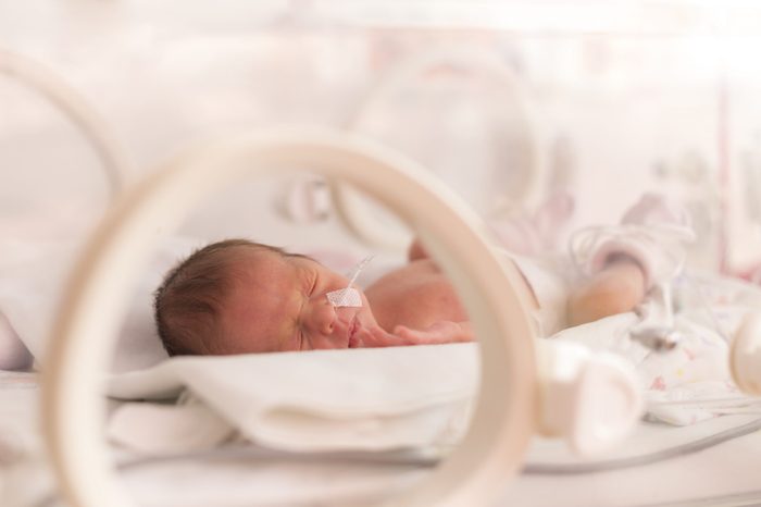 Premature newborn baby girl in the hospital incubator after c-section in 33 week