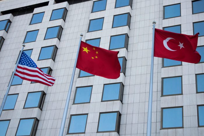 flags of America, China and Turkey on the background of the business building