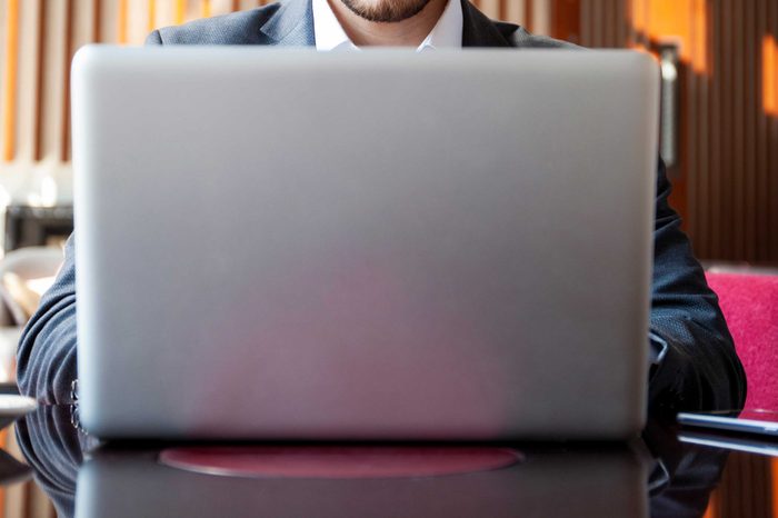 Young businessman working on laptop, sitting in hotel lobby waiting for someone