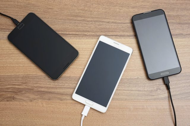 Mobile smart phones  charging on wooden desk