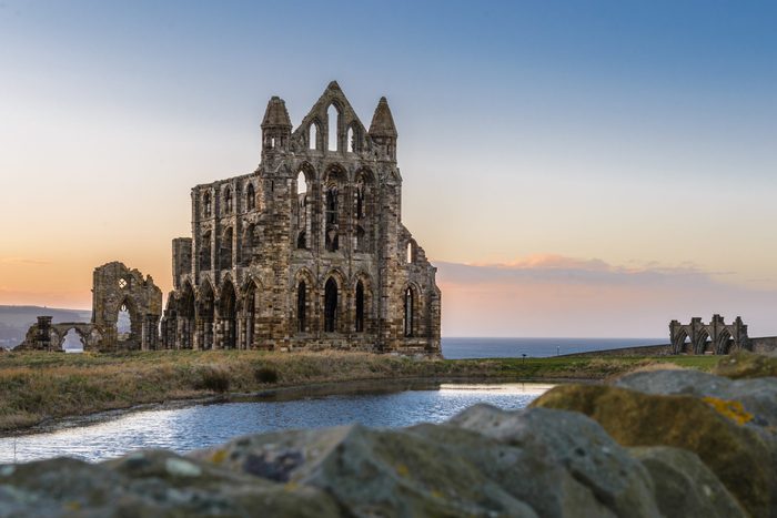 Stone ruins of Whitby Abbey on the cliffs of Whitby, North Yorkshire, England at sunset.