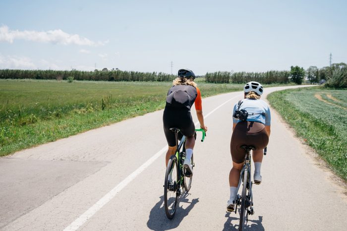 close up back view of a young fit strong fast cyclist during ride. athlete during summer vacation group ride at nature countryside. space for text. road cycling in action. training for competition.