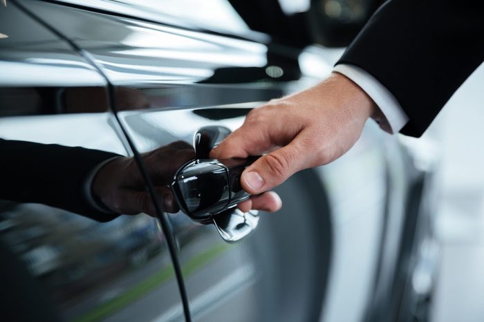 Close up of a male hand opening a car door at the dealership