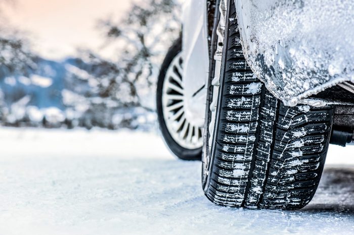 Tire in winter on snow road. Winter tires with car detail.