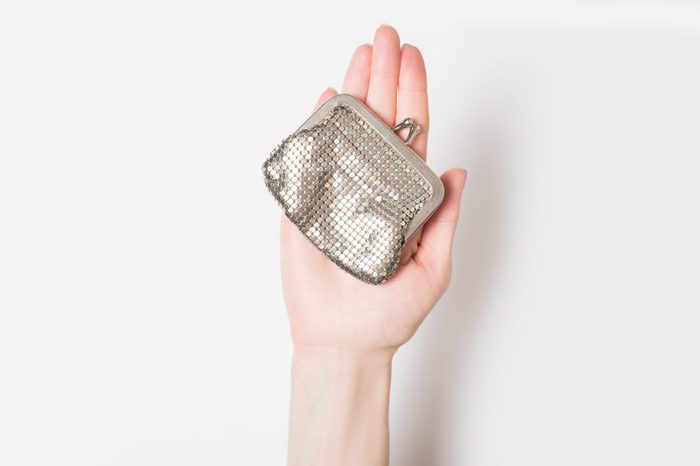 Metal purse on the female palm isolate on a light background.