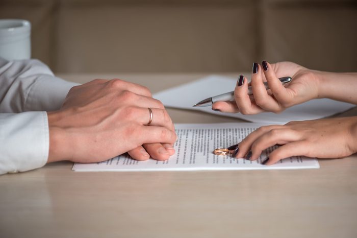 Wife and husband signing divorce (dissolution of marriage) documents, filing divorce papers prepared by lawyer, canceling marriage, performing legal or de jure separation, woman returning wedding ring