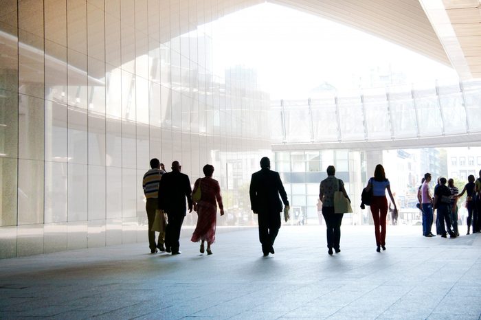 Employees going against the office. Panorama. Silhouettes.