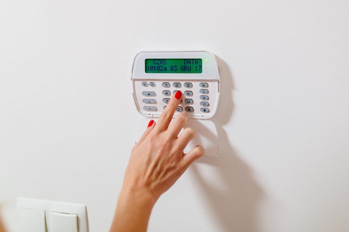 Woman entering security pin password on home security alarm keypad