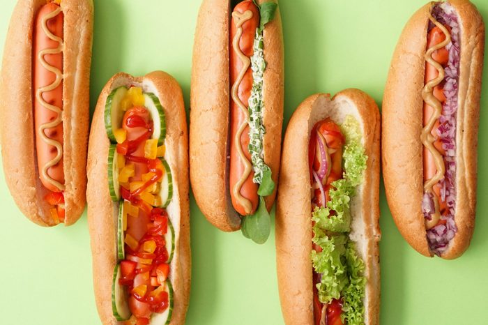 Tasty hot dogs on color background